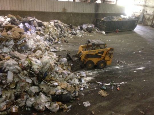 A WastAway employee operating a small bulldozer scoops up trash dumped into the warehouse in Morrison before transferring the waste to the area where the metals are separated for recycling. (Photo: Scott Broden/DNJ)